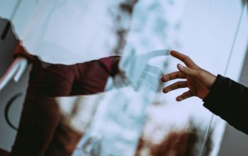 ablaküvegen keresztül összekapcsolódó kezek